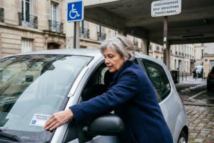 Femme plaçant une carte mobilité inclusion sur le tableau de bord d'une voiture garée sur une place handicapée en ville